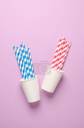 Photo for White cardboard cups with straws on a pink background. Party, birthday accessories - Royalty Free Image