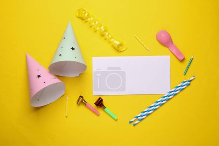 Tapas de cono de cumpleaños con accesorios de fiesta, banner en blanco sobre un fondo amarillo. Vista superior