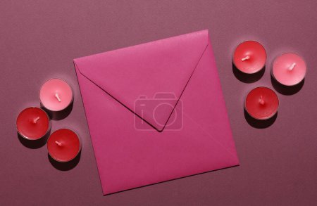 Envelope with Aroma tea candles on red background. Romantic, love concept. Top view.