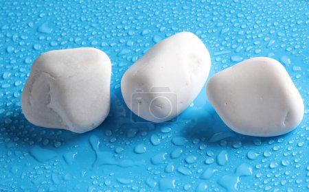 Photo for White pebbles on a blue background with water drops. spa, relaxation therapy - Royalty Free Image