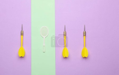 Leisure. Miniature Batbinton racket and darts on pastel background. Minimalism
