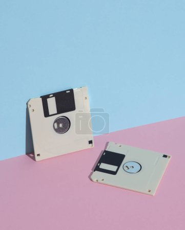 Téléchargez les photos : Disques disquettes sur fond bleu rose. Rétro années 80. Une technologie obsolète. Mise en page créative, minimalisme, nature morte minimale à la mode - en image libre de droit