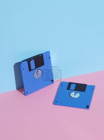 Téléchargez les photos : Disques disquettes bleus sur fond bleu rose. Rétro années 80. Une technologie obsolète. Mise en page créative, minimalisme, nature morte minimale à la mode - en image libre de droit