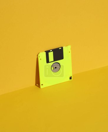 Téléchargez les photos : Disque souple sur fond jaune. Rétro années 80. Une technologie obsolète. Mise en page créative, minimalisme, nature morte minimale à la mode - en image libre de droit
