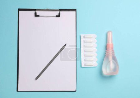 Visit to the gynecologist, Women's health. Clipboard, vaginal enemas and suppositories on a blue background. Top view