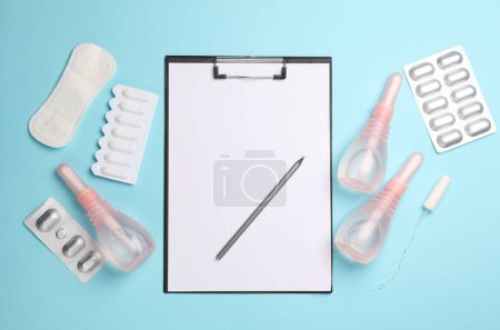 Visit to the gynecologist, Women's health. Clipboard, vaginal enemas, and pills on blue background. Top view