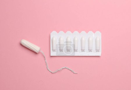 Women's health, treatment of women's diseases. Vaginal suppositories and tampon on pink background. Flat lay
