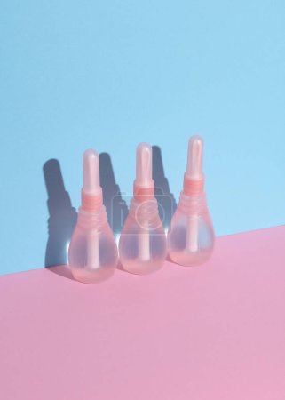 Three vaginal enemas on a pink blue background. Women's health. Creative layout