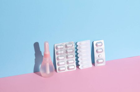 Vaginal enema and suppository, pills blisters on blue pink background. Women's health