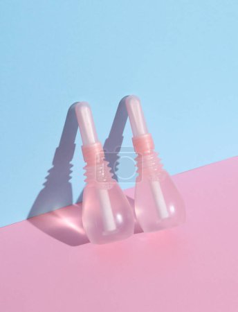Two Vaginal enemas on blue pink background. Women's health