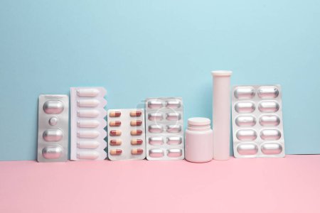 Various medicines, blisters of pills on a blue-pink background. Creative layout, minimalism medicine concept