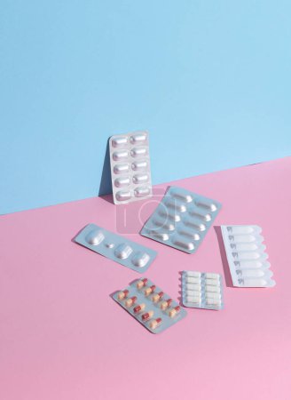 Divers médicaments, plaquettes thermoformées de pilules sur fond bleu-rose. Mise en page créative, concept de médecine minimaliste