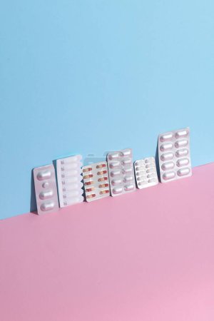 Various medicines, blisters of pills on a blue-pink background. Creative layout, minimalism medicine concept
