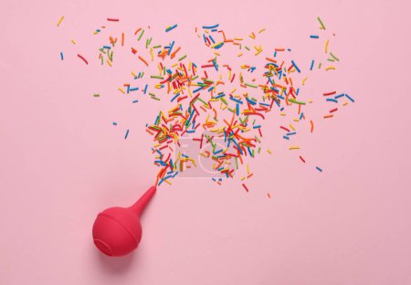 Enema with sprinkles on pink background. Minimal party concept
