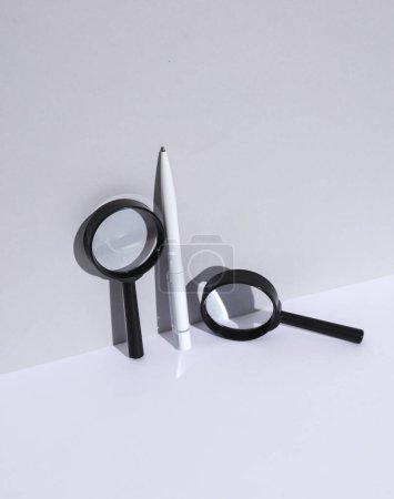 White pen and magnifying glasses on white background with shadow. Creative layout. Minimal business concept. Conceptual still life