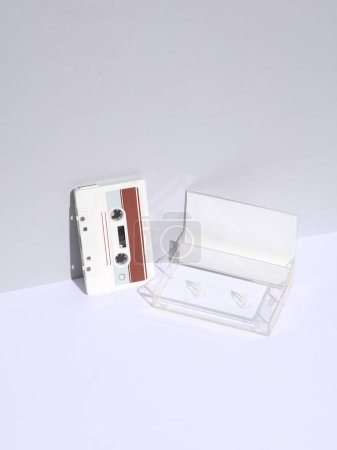 Weiße Retro-Audio-Kassette der 80er Jahre mit Box auf weißem Hintergrund mit Schatten. Kreatives Layout, Minimalismus, Musikliebhaber