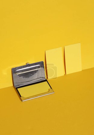 Téléchargez les photos : Cartes de visite blanches avec boîte en métal sur fond jaune avec ombre. Mise en page créative - en image libre de droit