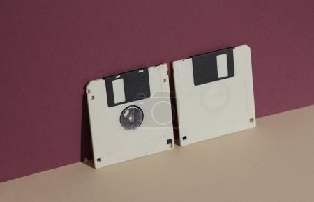 Téléchargez les photos : Disques disquettes rétro des années 80 sur fond bordeaux avec ombre. Mise en page créative, minimalisme - en image libre de droit