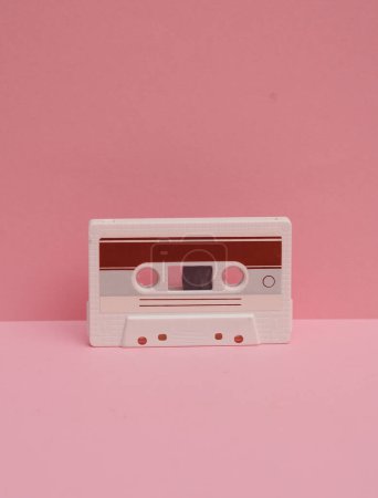 Veraltete Technologien. Audio-Kassette im Retro-Stil der 80er Jahre auf rosa Hintergrund. Kreative Gestaltung
