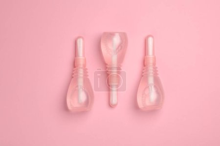 Three vaginal enemas on a pink background. Women's health