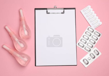 Visit to the gynecologist, Women's health. Clipboard, vaginal enemas, and pills on a pink background. Top view