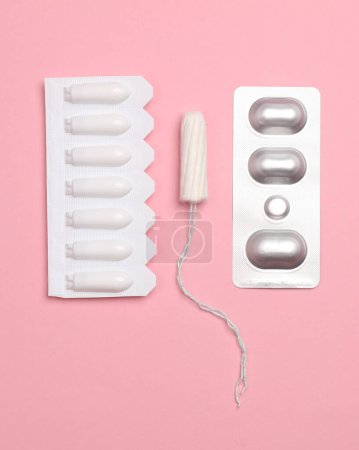 Photo for Vaginal suppositories, a tampon and a blister of pills on a pink background. Women Health - Royalty Free Image