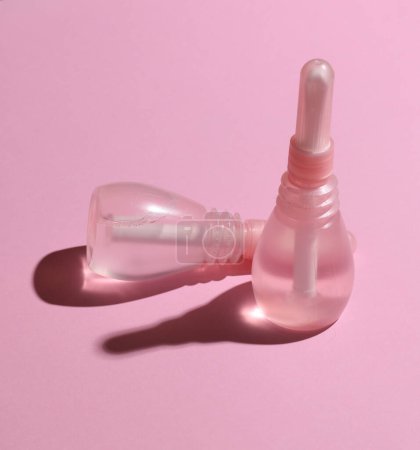 Dos enemas vaginales sobre un fondo rosa. Salud de la mujer
