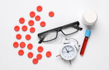 Rote Blutkörperchen Modell, Reagenzglas, Uhr, Pillen und Brille auf weißem Hintergrund. Flache Lage