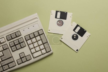 Retro keyboard and floppy disks on a green background. Top view
