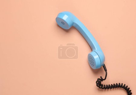 Retro blue telephone receiver on a pink background
