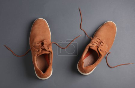 Foto de Zapatos de gamuza para hombre con cordones desatados sobre fondo gris - Imagen libre de derechos