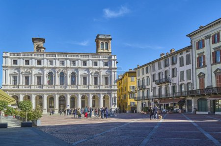 Téléchargez les photos : Brergamo, Italie - 7 mars 2017 : Les gens sur la vieille place habiter le palais blanc Civic Lybrary sur la gauche - en image libre de droit