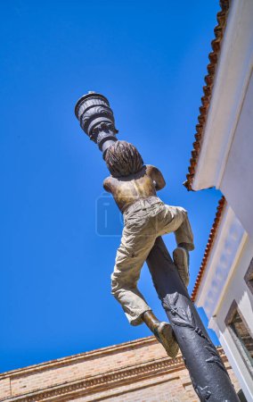 Foto de Buzios, Brasil - 3 de enero de 2023: Una escultura anónima que reproduce a un adolescente trepando una farola en el casco antiguo - Imagen libre de derechos