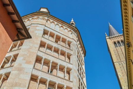 Photo for Parma, Italy, upward view of the octagonal Baptistery of pink marble in Lombard Romanesque style and the Cathedral bell tower - Royalty Free Image
