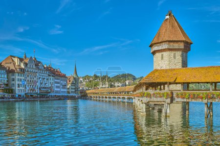 Téléchargez les photos : Lucerne, Suisse - 13 juillet 2022 : Le pont en bois couvert de la chapelle avec le château d'eau octogonal sur la rivière Reuss et la vieille ville en arrière-plan - en image libre de droit