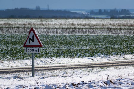Photo for Snowy countryside landscape with sunshine and a road sign, dangerously slippery - Royalty Free Image