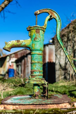 Old hand water pump on a well in the garden, watering and saving water, rural environnement