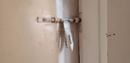 Téléchargez les photos : Vue rapprochée d'un vieux gros loquet blanc de attaché à la porte en fer - en image libre de droit