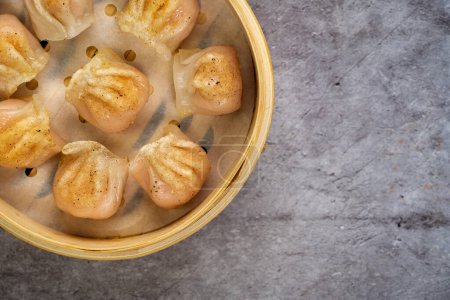 Photo for Homemade dumplings dim sum close-up in a bamboo steamer box on table. Horizontal top view from above - Royalty Free Image