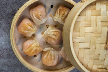 Photo for Homemade dumplings dim sum close-up in a bamboo steamer box on table. Horizontal top view from above - Royalty Free Image