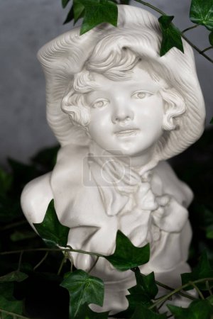 Photo for Germany Stature Sculpted head, head carved from white stone, Girl with a antique hat.with green leaves - Royalty Free Image