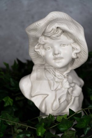 Foto de Alemania Estatura Cabeza esculpida, cabeza tallada en piedra blanca, Niña con un sombrero antiguo.con hojas verdes - Imagen libre de derechos