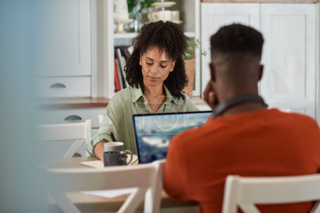 Photo for Young multiracial couple working remotely online from home together at a dining room table - Royalty Free Image