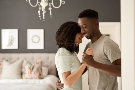 Photo for Smiling young multiracial couple dancing arm in arm together in their bedroom in the morning - Royalty Free Image