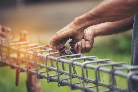 Téléchargez les photos : Construction Hommes mains flexion coupe clôtures métalliques barre d'armature des travaux en béton. Les mains des travailleurs à l'aide d'une pince fil de fer. Travailleur extérieur utilisant des pinces à cintrer, travaux de construction - en image libre de droit