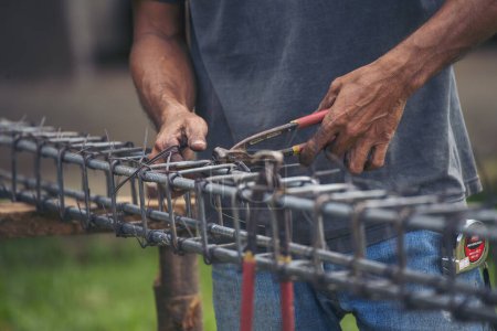 Téléchargez les photos : Construction Hommes mains flexion coupe clôtures métalliques barre d'armature des travaux en béton. Les mains des travailleurs à l'aide d'une pince fil de fer. Travailleur extérieur utilisant des pinces à cintrer, travaux de construction - en image libre de droit
