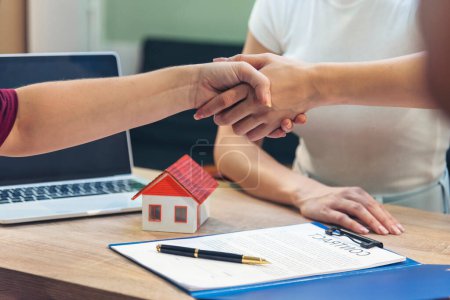 Close up Diversity women agent hands office desk. Crop Women handshake sign on insurance mortgage sale document. Businesswoman shakes hands customer dealing real estate house agent signing contract