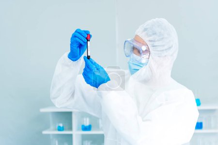 Scientist man holding sample blood test tube in science laboratory. Doctor clinic healthcare technician lab testing blood sample diagnosis. Asian man scientist working in hiv testing medical lab.
