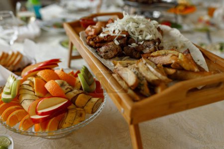 Shish kebab, potatoes and lavash on a wooden board. apples, bananas and orange on a plate