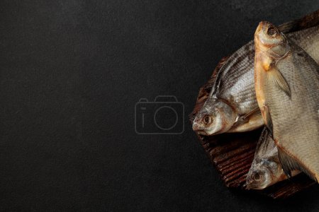 Dried bream fish on a cutting board on a black background